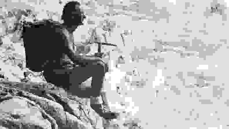 A black and white image of mountaineer and entrepreneur Vitale Bramani sitting on the edge of a cliff.
