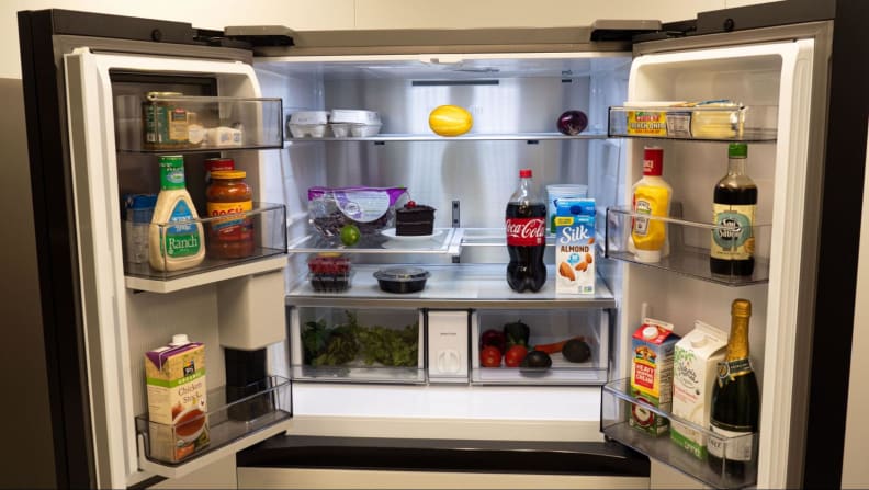 Les portes du réfrigérateur s'ouvrent grandes, révélant toutes sortes d'aliments et de condiments à l'intérieur.