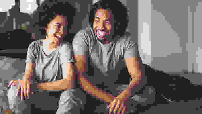 Cheerful black couple having fun while relaxing on sofa at home.