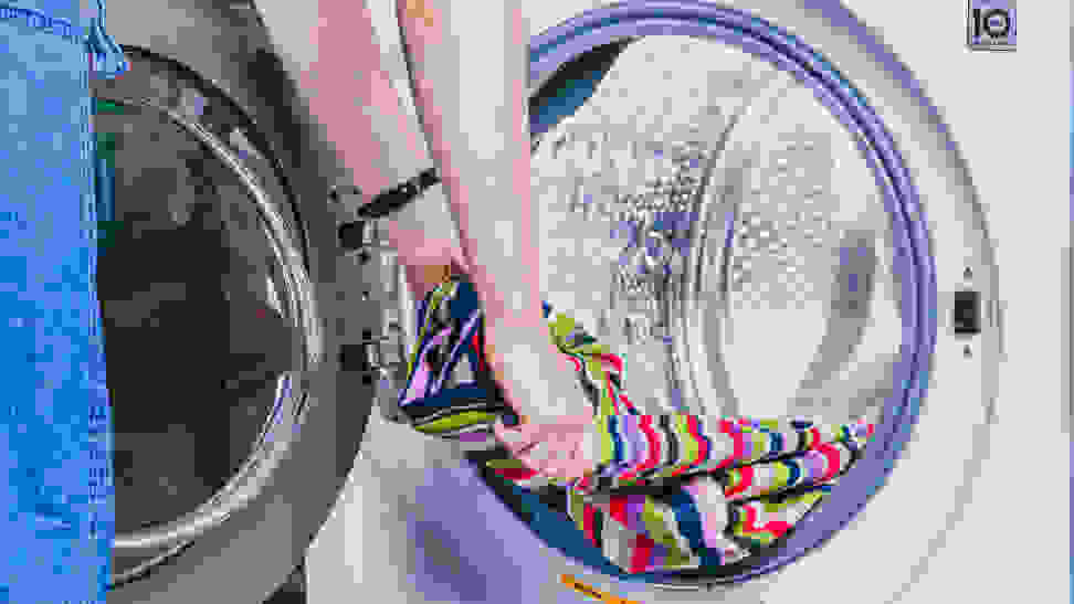 Someone pulls striped material out of a front-load washing machine