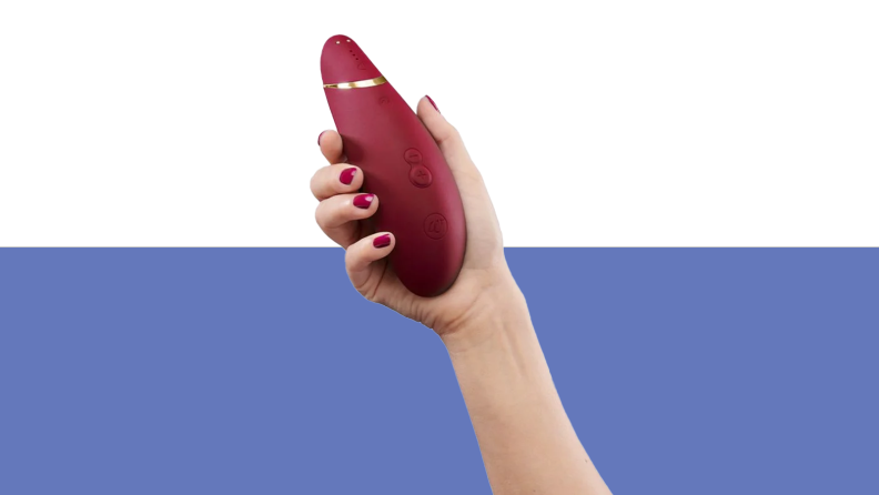 Hand holding The Womanizer Premium 2 in burgundy color.