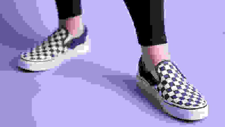 Close-up of a pair of feet wearing the Vans Checkered slip-ons.