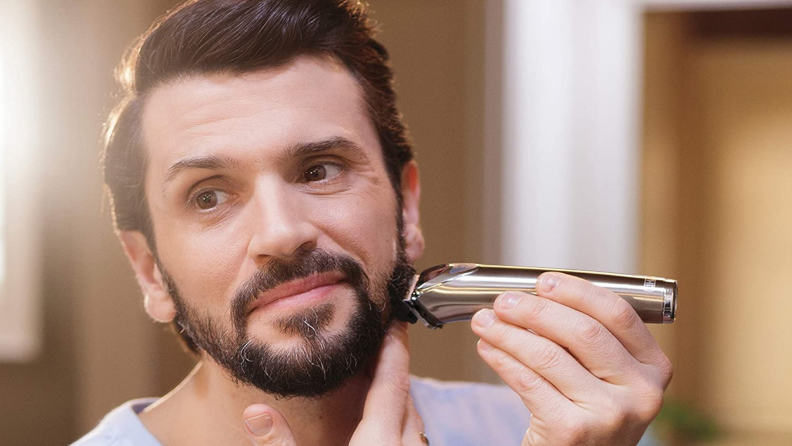 A man shaves his beard with a Wahl beard and nose trimmer.