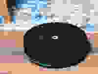 The iRobot Roomba Comobo Essential on a hardwood floor next to carpet.