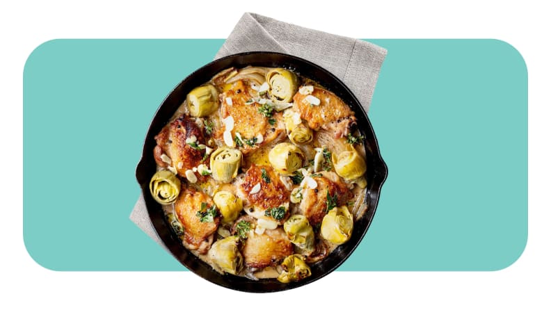 A cast iron serving dish with a prepared dish of meat and veggies.