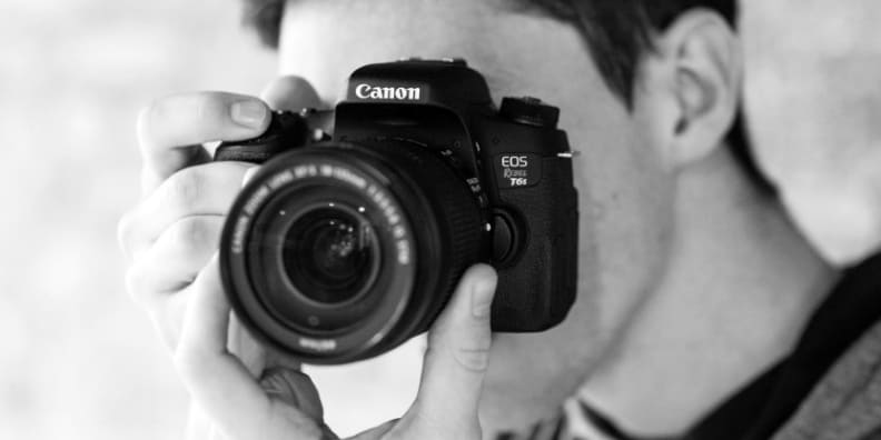 With a DSLR you want to support the camera's weight from underneath by grabbing the lens.