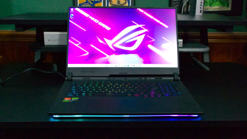 The Asus ROG Strix SCAR 17 (2023) open with a purple screensaver, on a desk.