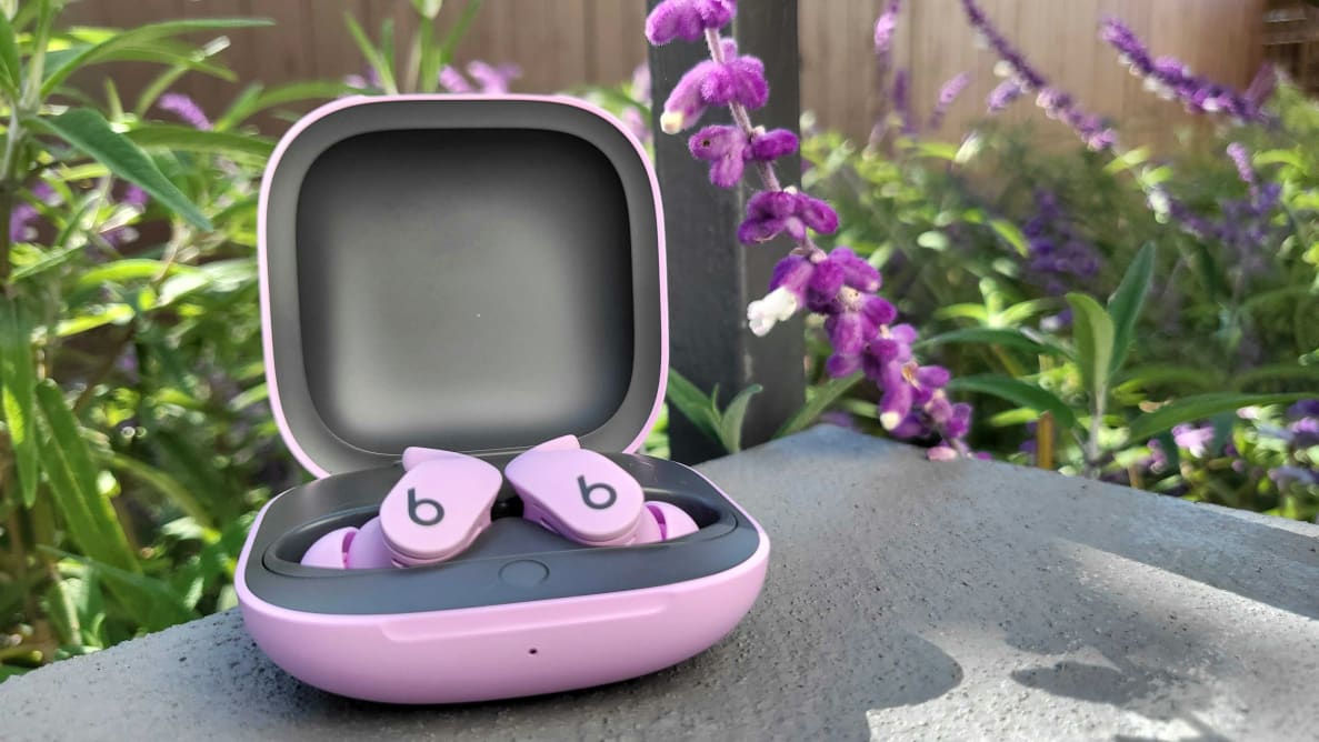 The Beats Fit Pro, sitting in their open case, in front of purple Mexican sage