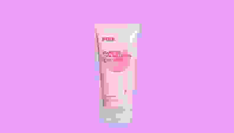 粉红色背景下的一瓶乳液。