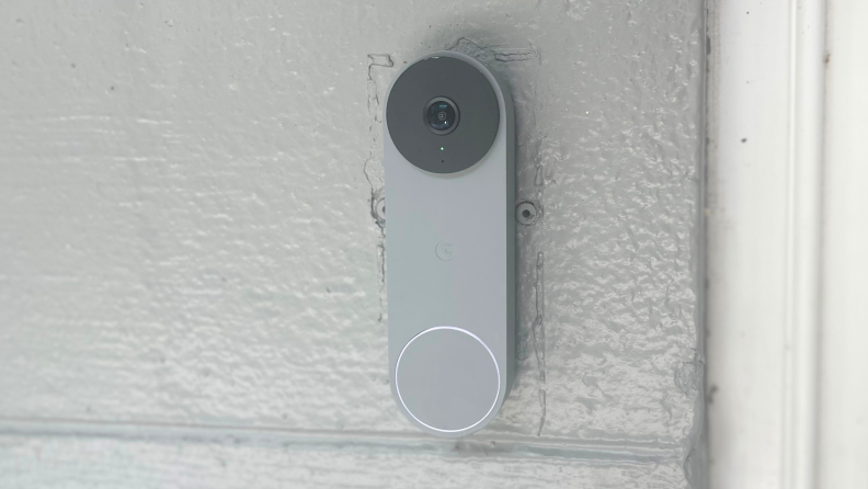 A gray Nest video doorbell hanging on a gray house