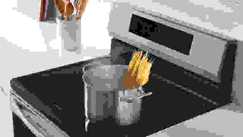 A pot with spaghetti noodles sits atop a convection range.