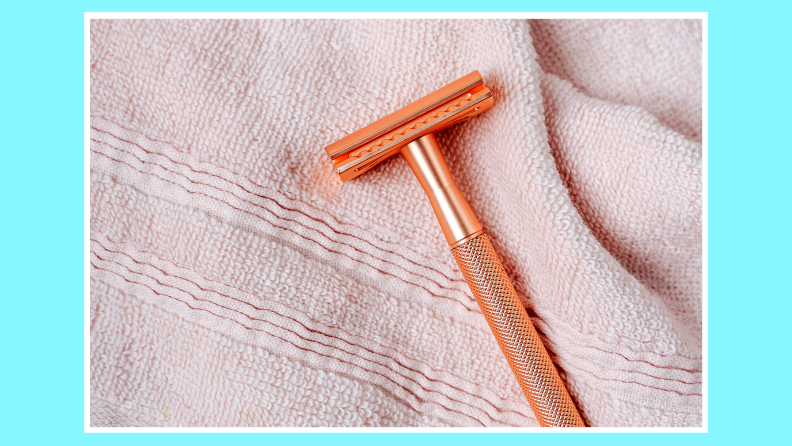 Orange shaving razor lying on top of razor.