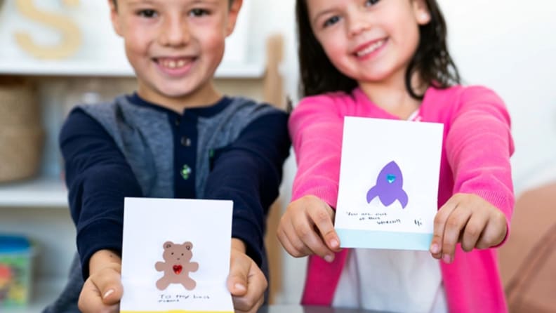 Two children hold holiday cards.