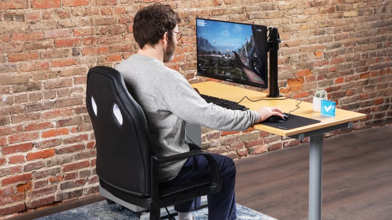 A person sitting in an Amazon Basics Racing/Gaming style office chair using a computer monitor.
