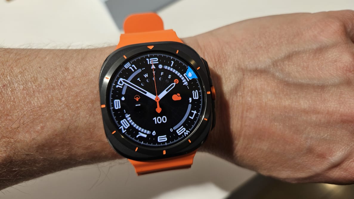 Person wearing the Samsung Galaxy Watch Ultra on their wrist with a neon orange band.
