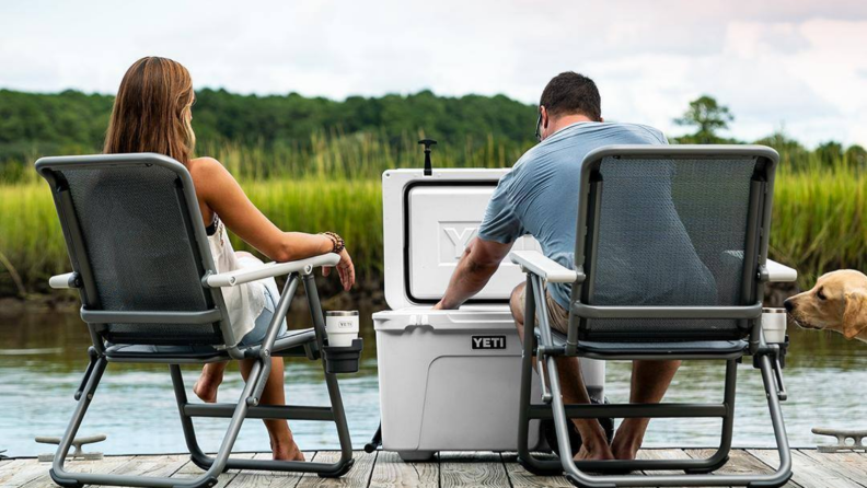 Couple sitting on a deck with a Yeti cooler between them