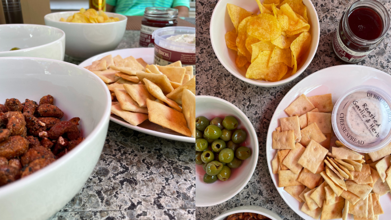 Bowls of chips, crackers, olives, and nuts sit on a counter.