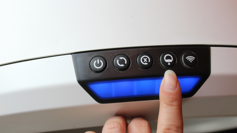A finger pointing to a button on the Litter-Robot 4 control panel