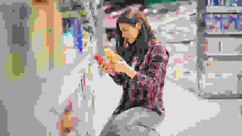 A photo of a woman picking out sunscreen in a store.