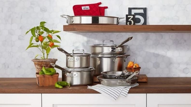 Several pots and pans are arranged neatly on a kitchen counter, along with some uncut peppers.