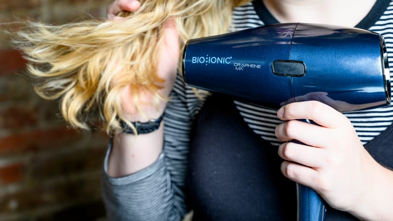 A hair dryer blow-drying long blond hair.