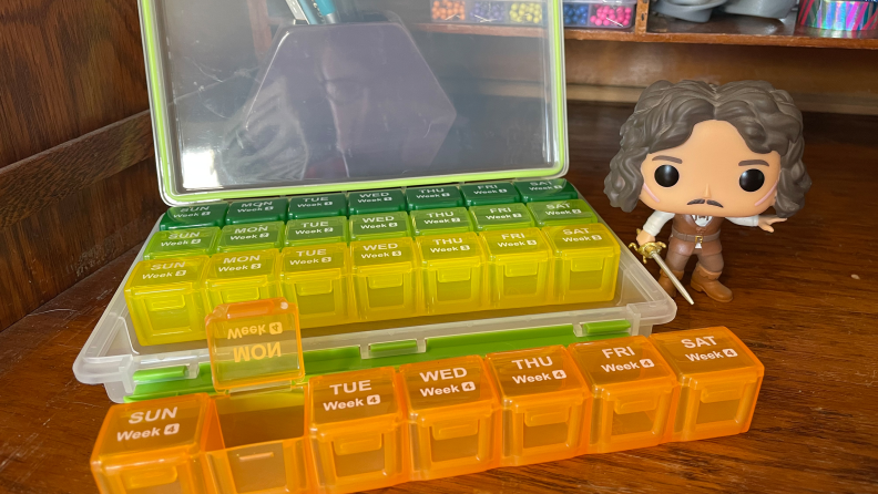 The Auvon Monthly Pill Organizer next to a Funko Pop figurine