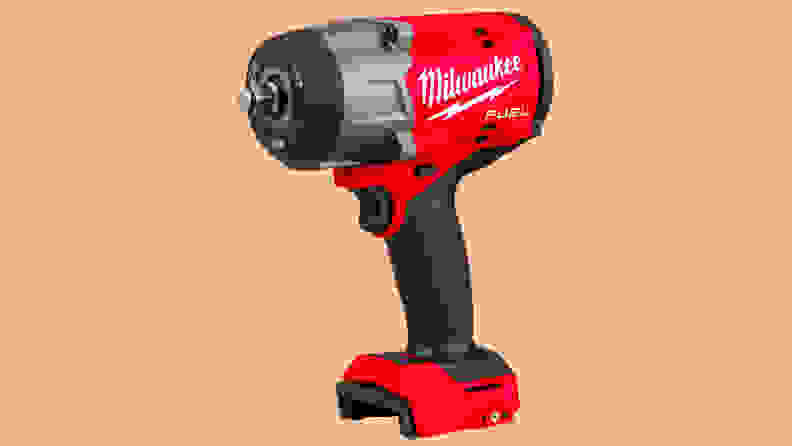 A close-up of the Milwaukee torque impact wrench on a peach-colored background.