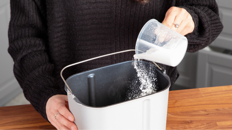 A person pouring flour into the bread maker.