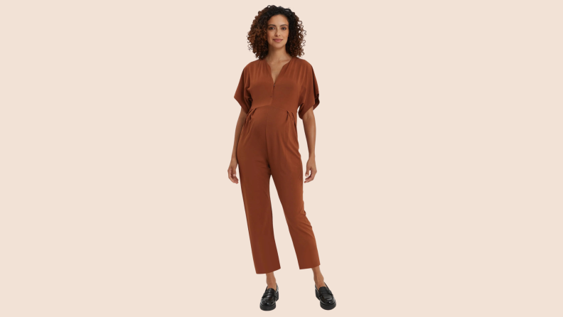 A woman wearing the Nom Maternity Filipa Nursing Jumpsuit in the color brown.