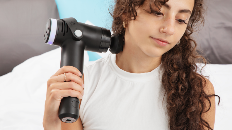 A woman holds the Prosage Thermo Copper Massage Gun to her neck