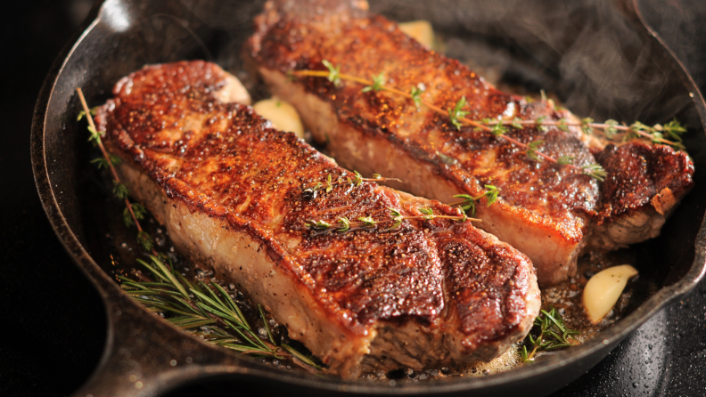 Steaks cooking in cast iron pan