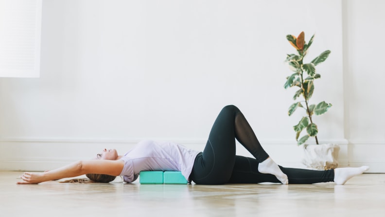 A woman lying on her back on two yoga blocks.
