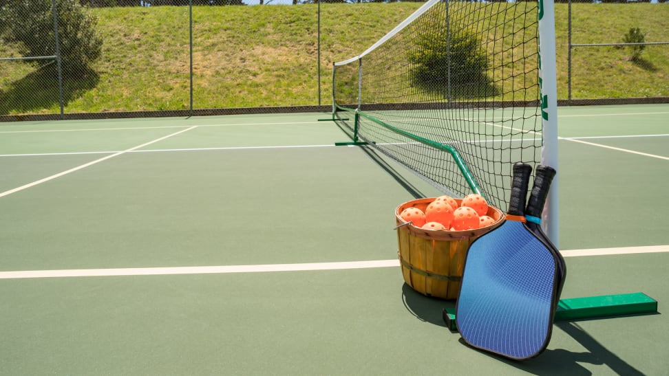 Pickleball rackets and balls on court next to net