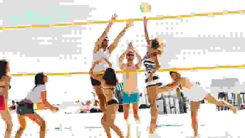 A group of people playing beach volleyball.