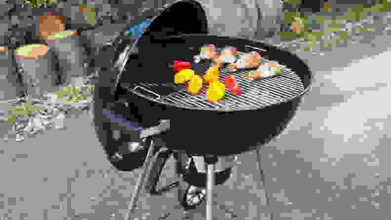 A charcoal grill with meat and vegetables on it.