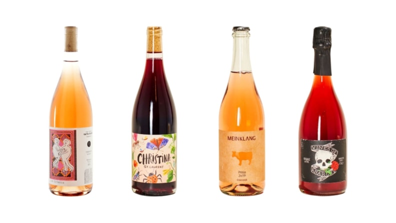Four bottles of brightly colored natural wine bottles against a white background.