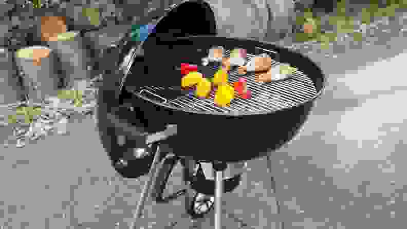 Charcoal grill cooking chicken and peppers.