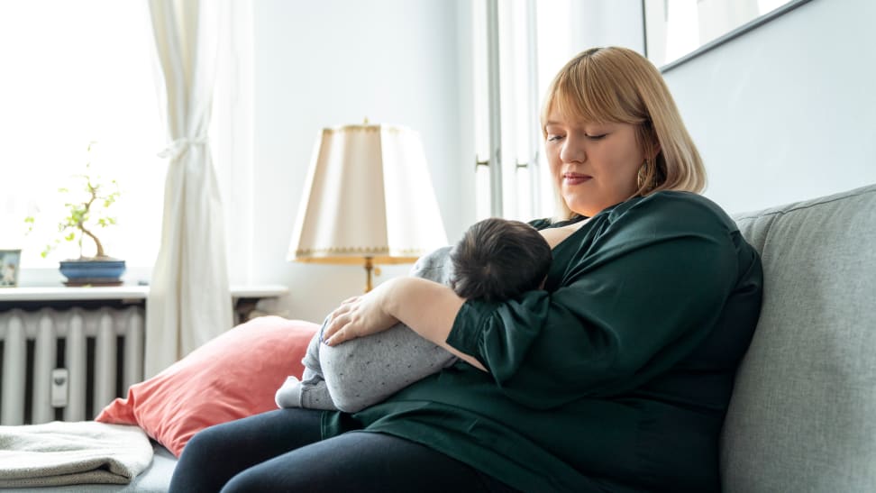 Mother sitting on a couch holding a new baby