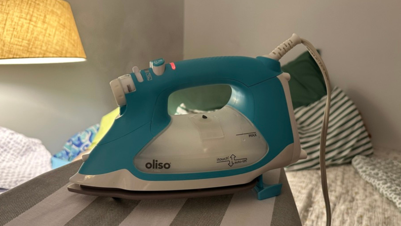 The Oliso steam iron sitting on an ironing board.