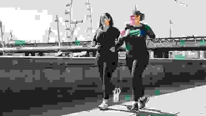 two woman in activewear walking on bridge
