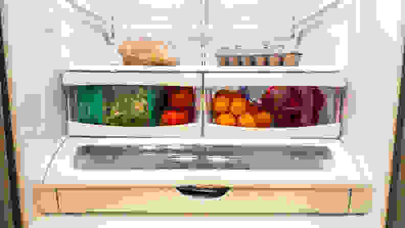 A refrigerator is stocked with groceries: bread, eggs, broccoli, tomatoes, apples, and oranges.