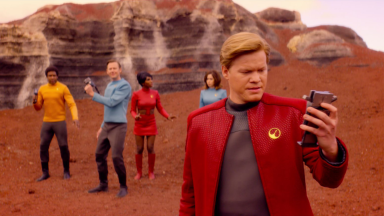A still from the Star Trek episode of 'Black Mirror,' featuring the cast of the episode in Star Trek themed outfits on a planet of rocks and red dirt.
