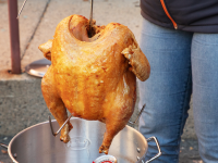 Fried turkey hanging above a pot outdoors