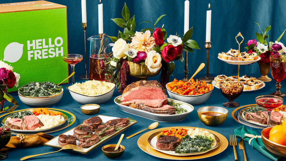 A spread of holiday food and a HelloFresh box on a blue tablecloth.