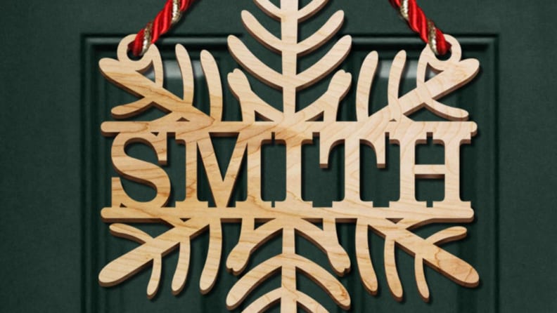 Accroche-porte en bois avec flocon de neige indiquant 'Smith' sur une porte verte.