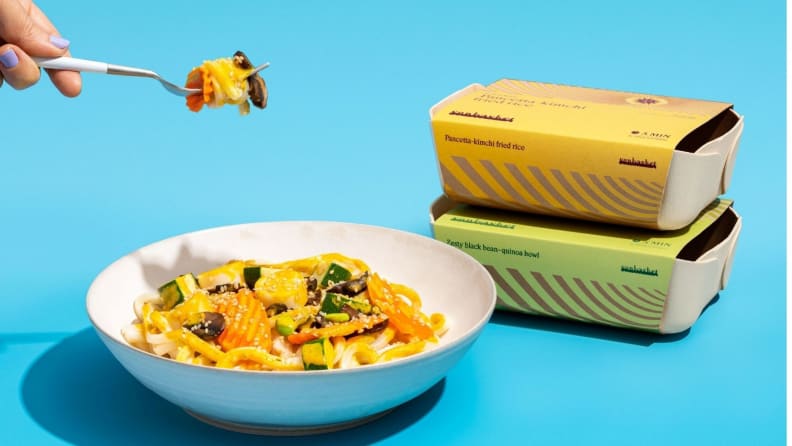 A person holding a fork filled with pasta and the bowl filled with pasta sitting beneath.