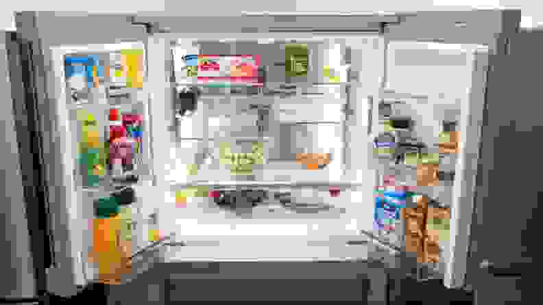 A close-up of the open refrigerator compartment, fully stocked with food.