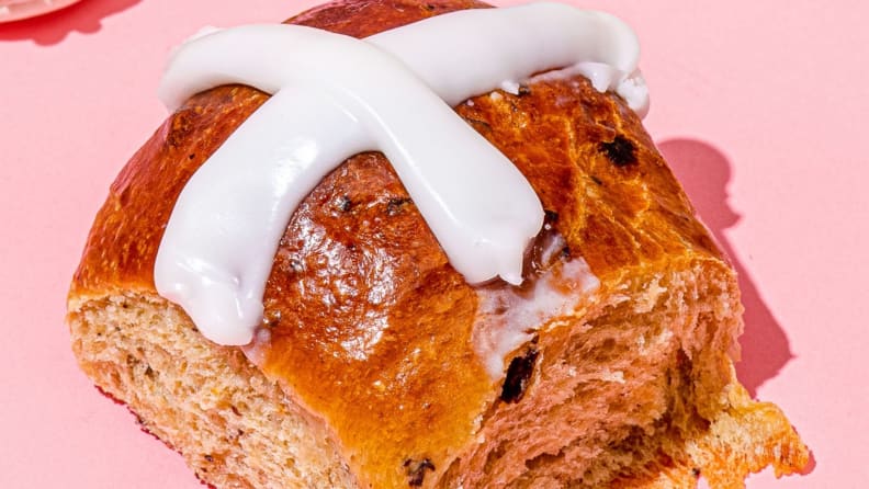 A close-up photo of hot cross buns, topped with the traditional white icing in a cross pattern.