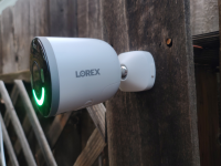 Lorex 4K Spotlight mounted on wooden fence outdoors.