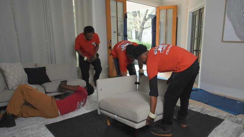 Four movers dismantling a sofa set before packing